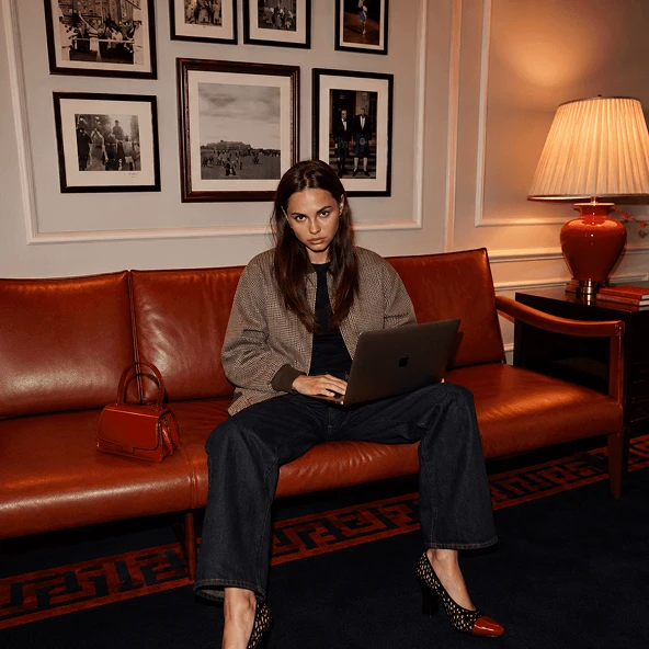 A woman working on a laptop on a leather sofa