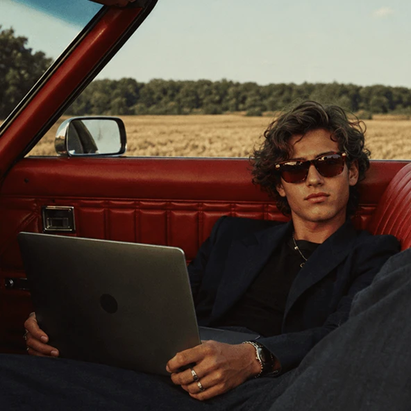 A man with a laptop in a convertible