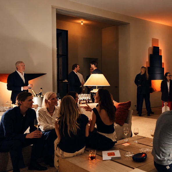 Guests in suits talking over drinks in a warmly lit lounge